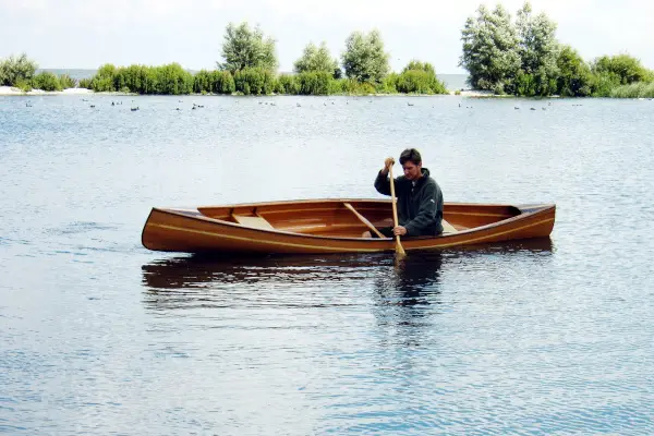 persoon peddelt in een houten Canadese kano