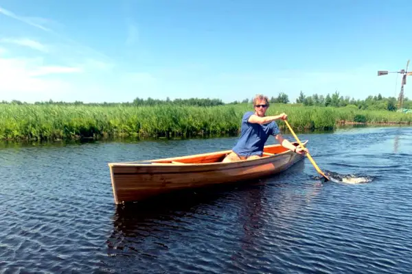 Man vaart eenpersoons houten kano Singel