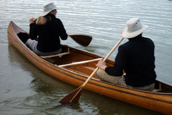 kanovaarders in houten kano op water