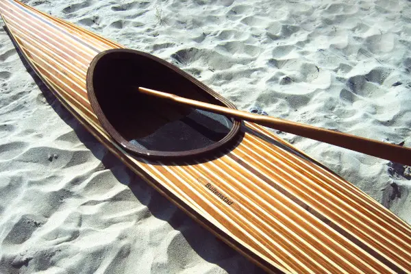 Houten kajak met groenlandpeddel op het strand